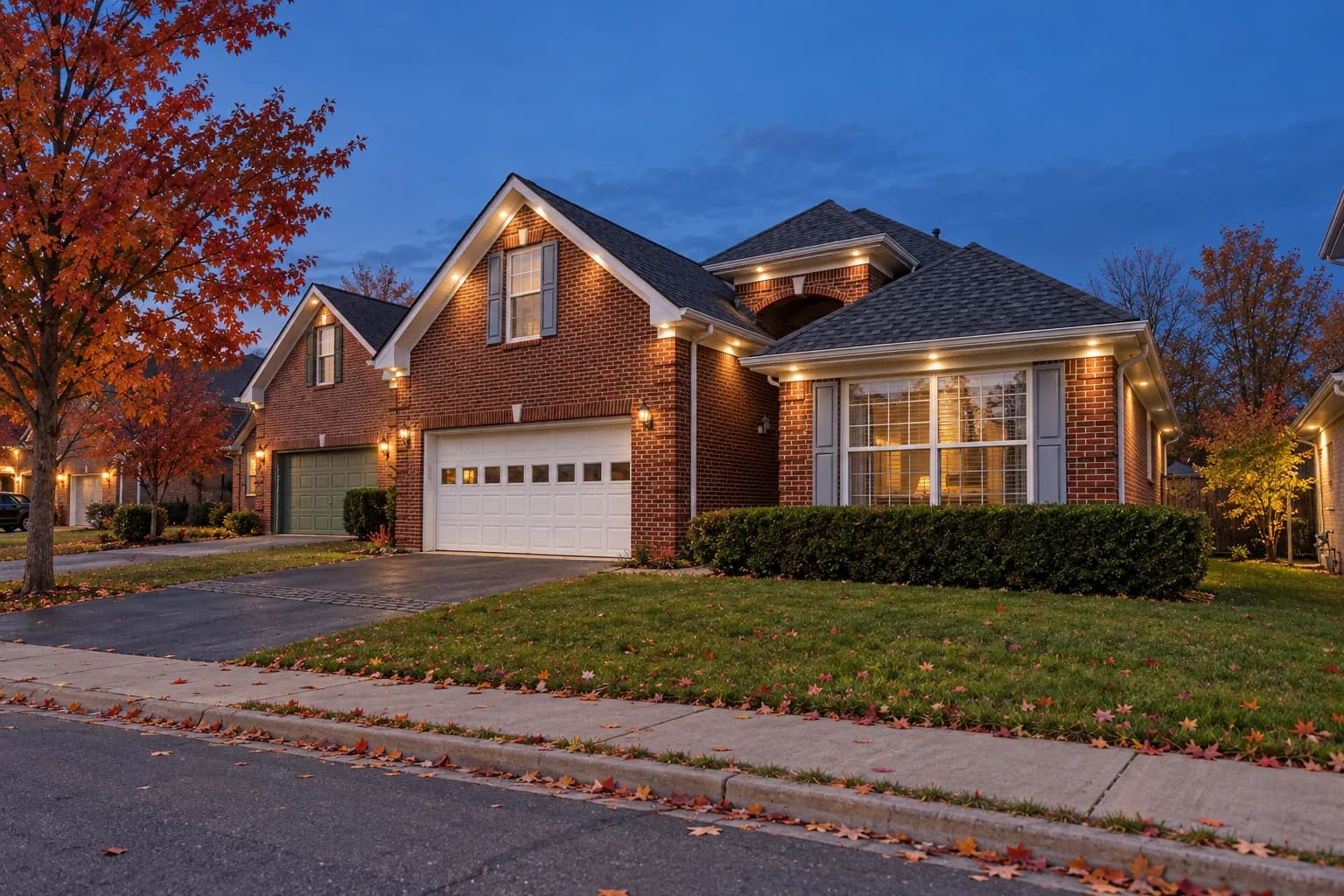 Two-storey red brick Brampton home at dusk with warm white soffit pot lights evenly spaced along the roofline and over the double garage