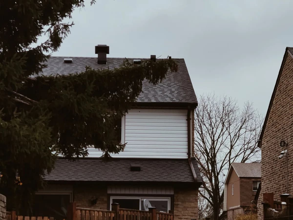 Two-storey Toronto home with siding above a brick base, photographed after rain